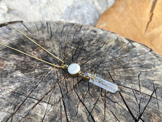 Pendant rock crystal with operculum with spirals, dots and small stone, brass