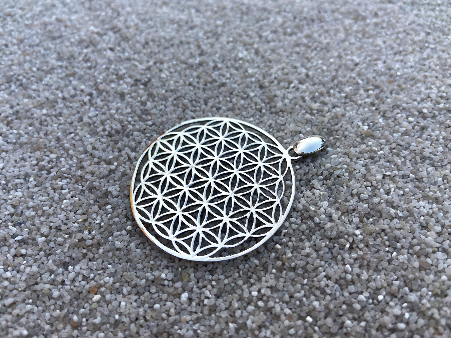 large pendant with the motif of the flower of life made of silver