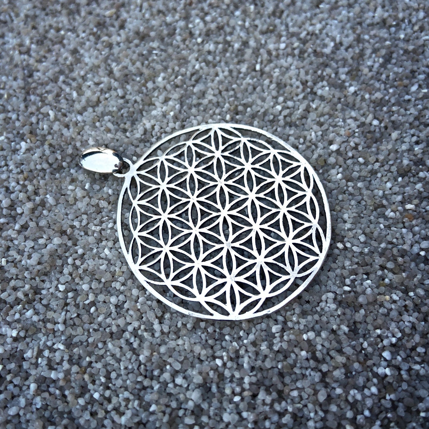 large pendant with the motif of the flower of life made of silver