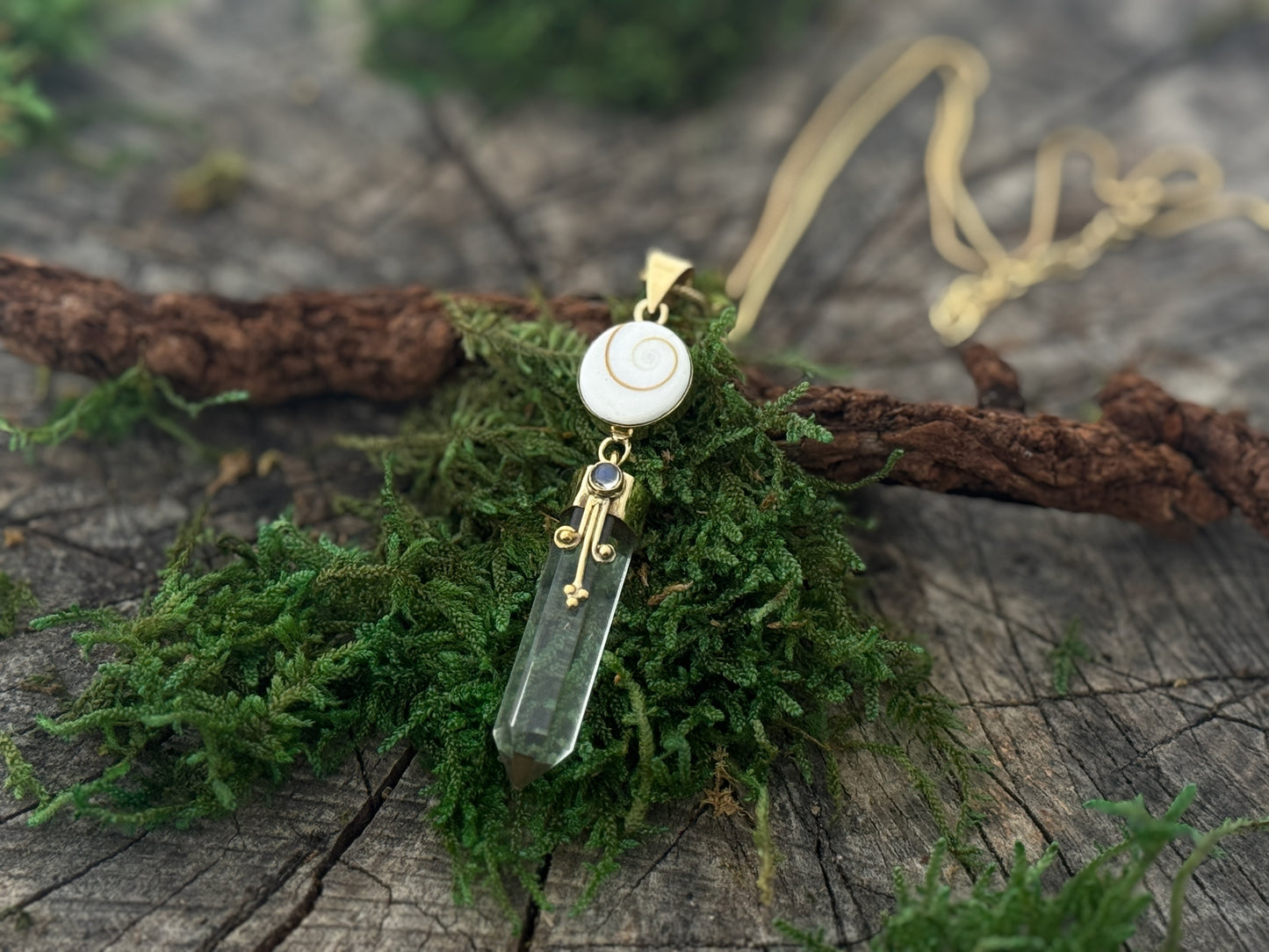 Pendant rock crystal with operculum with spirals, dots and small stone, brass 